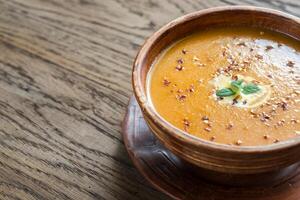 Bowl of spicy pumpkin cream soup on the wooden table photo