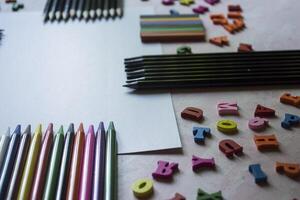 multicolor letras y conjunto de lapices en el mesa. vistoso de madera alfabeto y lapices en un mesa. foto