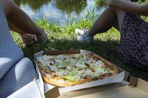Friends with pizza near the lake. photo