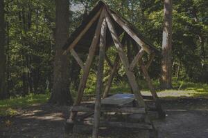 An old wooden pavilion in the forest. Peaceful place for relaxation. photo