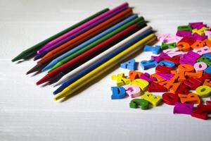 Multicolor letters and set of pencils on the table. Colorful wooden alphabet and pencils on a table. photo