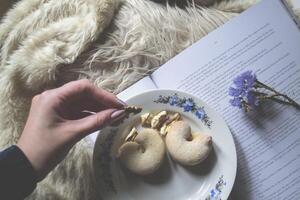 Coffee, cake and book. Woman holding a nut. Cozy atmosphere of home. photo