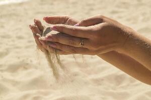 el arena es torrencial desde mujer manos. foto