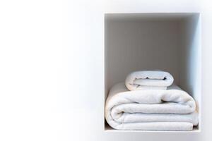 blanco toalla conjunto doblada apilar en un limpiar almacenamiento sencillo estante evocando un sentido de calma spa y bienestar en un aptitud ducha, baño, lavandería o lujo hotel foto