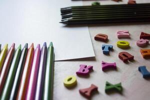 multicolor letras y conjunto de lapices en el mesa. vistoso de madera alfabeto y lapices en un mesa. foto