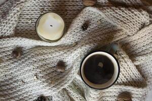 A cup of coffee and woolen scarf with decorations on a table. Coziness. photo