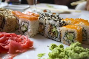 conjunto de Sushi rollos con vasabi y jengibre en un blanco lámina. foto