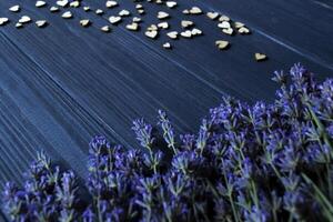 Lavender flowers and wooden love hearts on a dark blue wooden table. Beautiful romantic background with copy space. photo