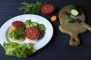 The sandwiches with vegetables on the plate. Vegetarian food. Ingredients for cooking on the table. photo