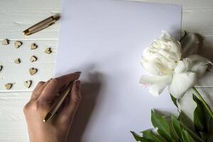 White paper, pen, peony and decor on the desk. Beautiful still life on the desktop. photo