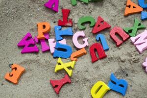 Multicolor wooden letters on a sand close up. photo