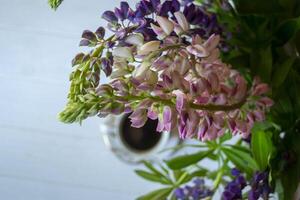 A cup of coffee and lupine flowers on a white wooden table. photo