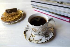 taza de café, libros y postre en un blanco de madera mesa. foto