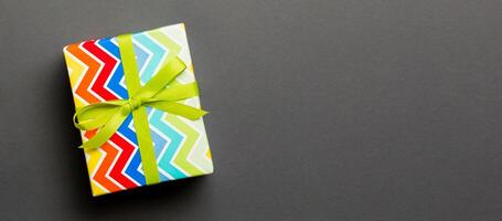 Top view Christmas present box with green bow on black background with copy space photo