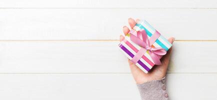 Top view of female hands holding christmas or other holiday handmade present box package in the palms, flat lay on white table background with copy space photo