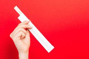 Woman's hand holding chopsticks in a pack on red background. Chinese food concept with empty space for your design photo