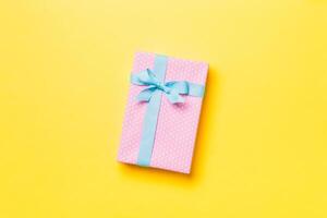 Gift box with blue bow for Christmas or New Year day on yellow background, top view with copy space photo