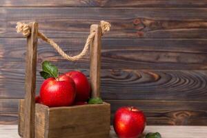 maduro rojo manzanas en de madera caja. en un blanco de madera antecedentes foto