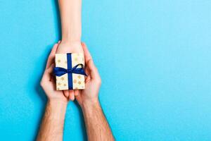 Top view of a woman and a man giving and receiving a present on colorful background. Love and relationship concept. Close up photo