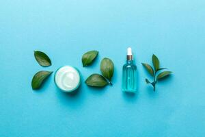 Organic cosmetic products with green leaves on color background photo