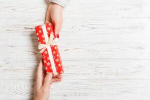 Top view of giving and receiving a gift on wooden background. Present in male and female hands. Love concept. Copy space photo