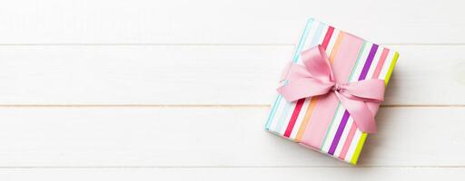 paper gift box with colored ribbon on white wood background. top view with copy space Christmas holiday concept photo