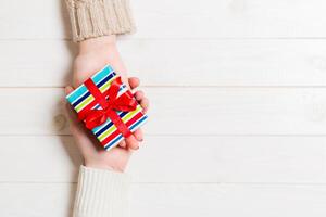 Top view of two people sharing a present on wooden background. Holiday and surprise concept. Copy space photo