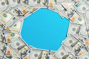 Frame made of dollars with copy space in the middle. Top view of business concept on blue background with copy space photo