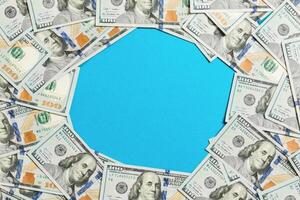 Frame made of dollars with copy space in the middle. Top view of business concept on blue background with copy space photo