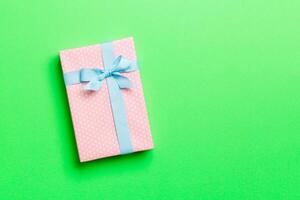 wrapped Christmas or other holiday handmade present in paper with blue ribbon on green background. Present box, decoration of gift on colored table, top view with copy space photo