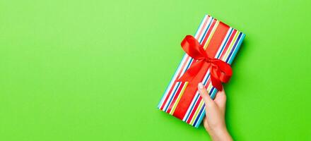 Top view of female hands holding christmas or other holiday handmade present box package in the palms, flat lay table background with copy space photo