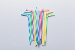 Drinking straws for party on Colored background. Top view of colorful plastic disposable straws for summer cocktails. different straws for juice with copy space photo