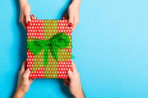 Top view of a man and a woman holding a gift on colorful background. Concept of giving and receiving a present with copy space photo