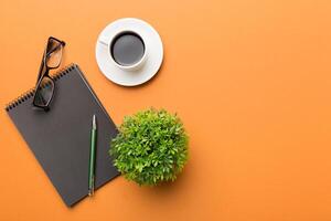 Modern office desk table with notebook and other supplies with cup of coffee. Blank notebook page for you design. Top view, flat lay photo