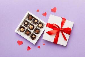 Delicious chocolate pralines in red box for Valentine's Day. Heart shaped box of chocolates top view with copy space photo