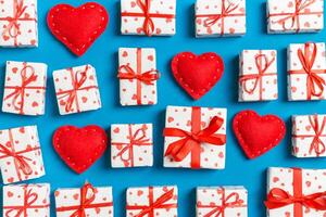 Composition of holiday white gift boxes and red textile hearts on colorful background. Valentine's day concept photo