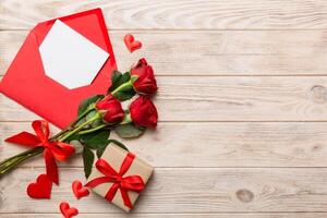 Valentine day composition with Envelope, rose flower and Red heart on table. Top view, flat lay. Holiday concept photo