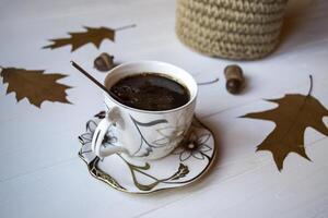un taza de café en un blanco de madera mesa, y decoración por roble otoño hojas. foto