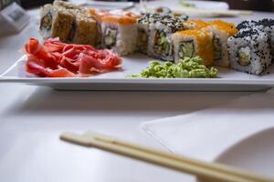 conjunto de Sushi rollos con vasabi y jengibre en un blanco lámina. foto