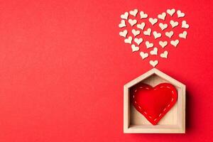 Top view of red textile heart in a wooden house decorated with small hearts on colorful background. Shape of heart. Home sweet home. Valentine's day concept photo