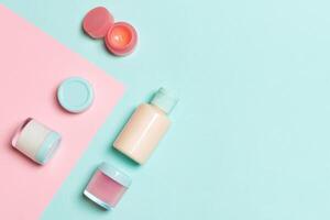 grupo de botellas de plástico para el cuidado del cuerpo composición plana con productos cosméticos sobre fondo rosa y azul espacio vacío para su diseño. conjunto de envases cosméticos blancos, vista superior con espacio de copia foto