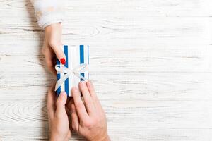 Top view of two people sharing a present on wooden background. Holiday and surprise concept. Copy space photo