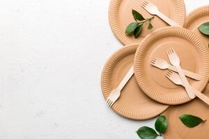 set of empty reusable disposable eco-friendly plates, cups, utensils on light white colored table background. top view. Biodegradable craft dishes. Recycling concept. Close-up photo