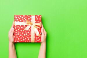 Top view of female hands holding christmas or other holiday handmade present box package in the palms, flat lay table background with copy space photo