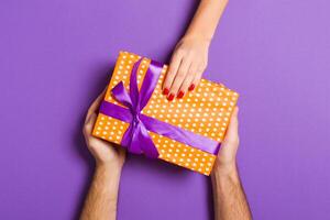 Top view of couple giving and receiving a gift on colorful background. Romantic concept with copy space photo