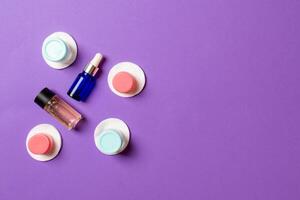 Set of travel size cosmetic bottles on colored background. Flat lay of cream jars. Top view of bodycare style concept photo