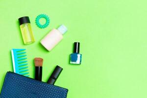 Make up products spilling out of cosmetics bag on green background with empty space for your design photo