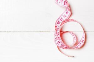 Top view of measure tape curtailed into a spiral with copy space. Concept of sewing accessory or healthy diet on wooden background photo