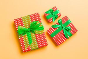 Gift box with green bow for Christmas or New Year day on orange background, top view photo