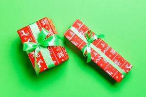 wrapped Christmas or other holiday handmade present in paper with green ribbon on green background. Present box, decoration of gift on colored table, top view photo